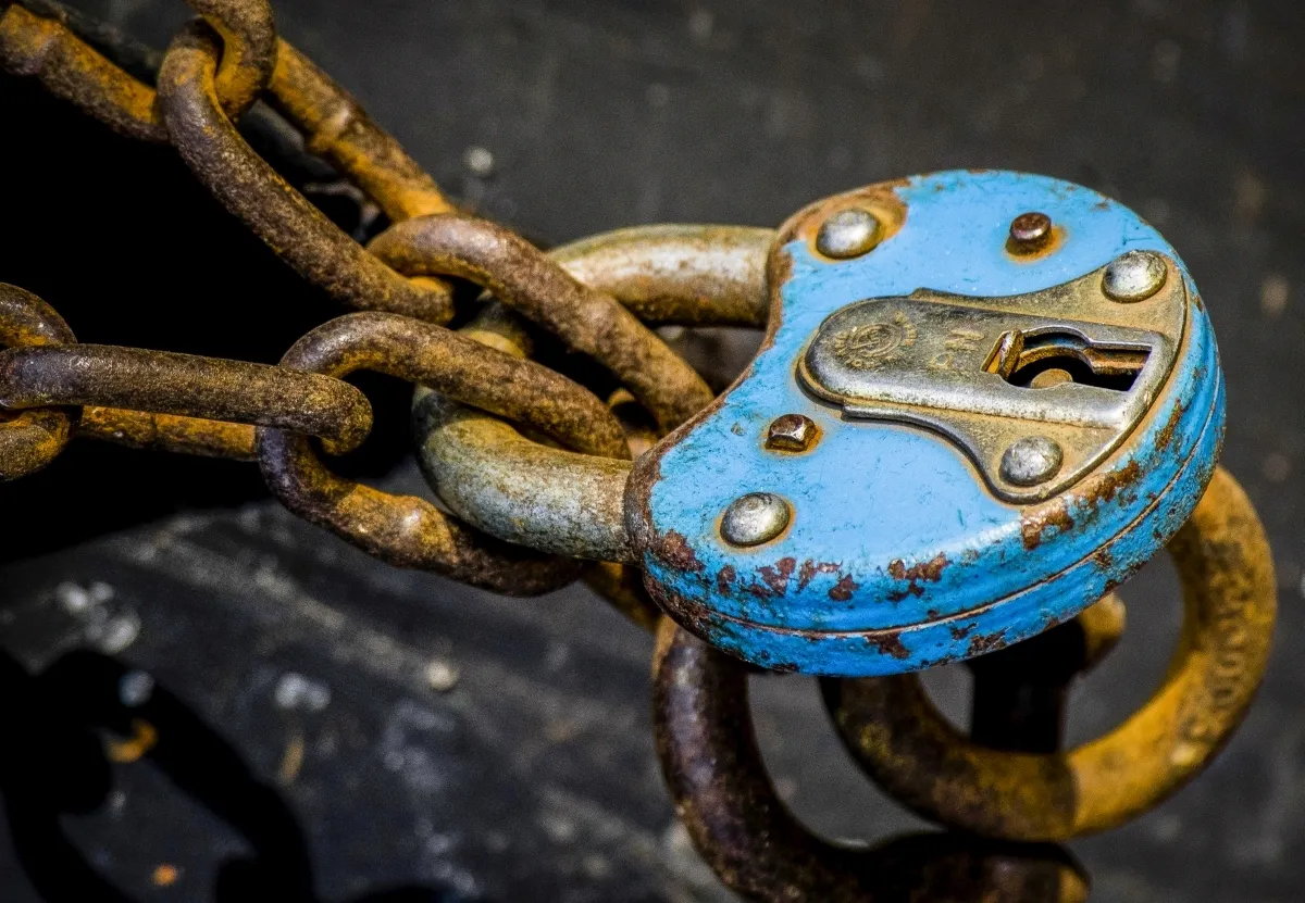 Blue padlock fastened to a rusted chain